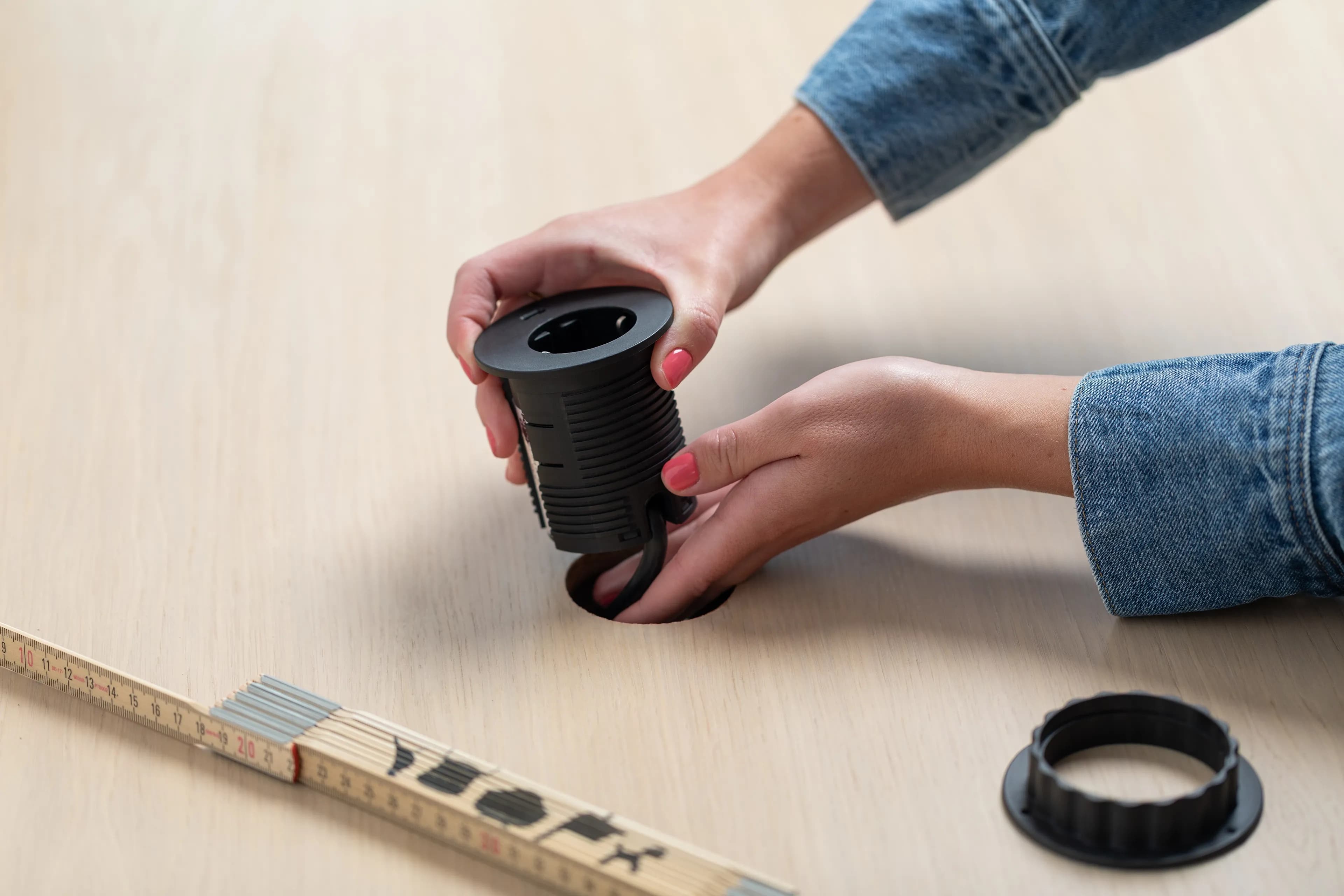 Image of a person installing electrical outlets in a tabletop.